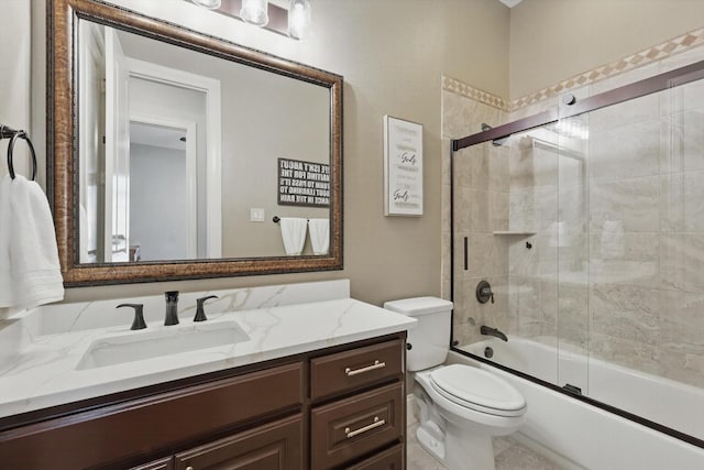 bathroom with toilet, bath / shower combo with glass door, and vanity