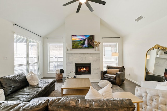 living room with hardwood / wood-style flooring, a high end fireplace, high vaulted ceiling, and ceiling fan