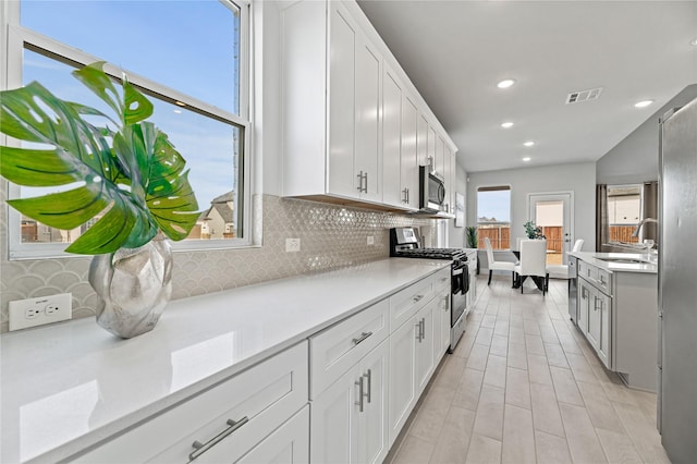 kitchen featuring white cabinetry, stainless steel appliances, and decorative backsplash