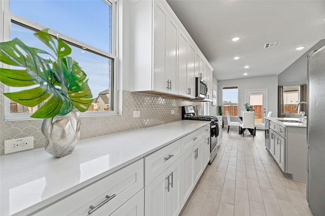 kitchen with light countertops, decorative backsplash, stainless steel appliances, and visible vents