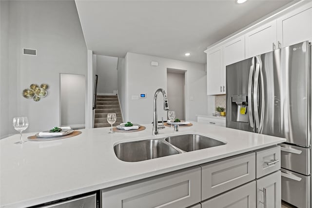 kitchen featuring visible vents, recessed lighting, light countertops, stainless steel fridge with ice dispenser, and a sink