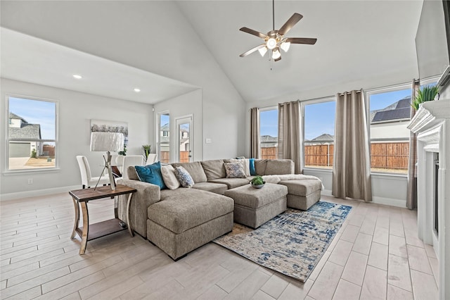 living area with baseboards, wood tiled floor, a ceiling fan, and high vaulted ceiling