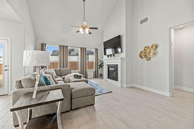 living room with light wood-type flooring, high vaulted ceiling, and ceiling fan