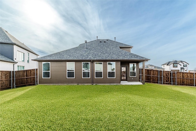 back of property with a fenced backyard, roof with shingles, a patio area, and a yard