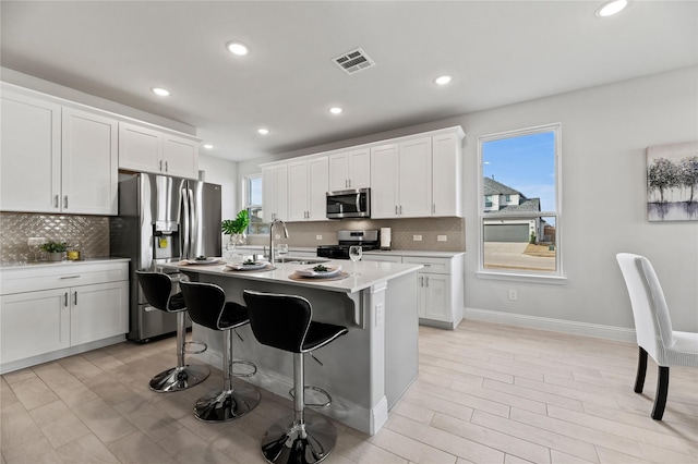 kitchen with a sink, tasteful backsplash, stainless steel appliances, and a wealth of natural light