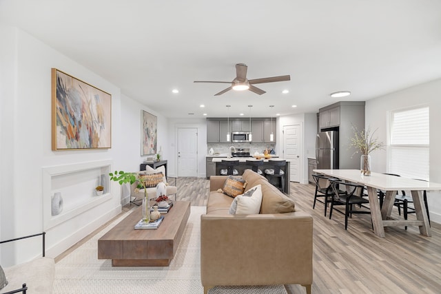 living room featuring ceiling fan and light hardwood / wood-style flooring