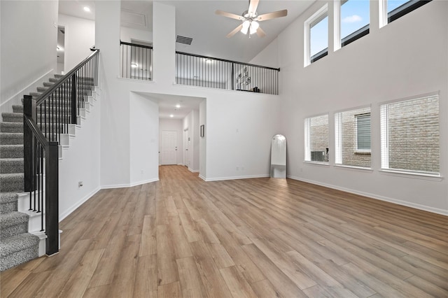 2408 Lundy Canyon St, Forney, TX 75126 - unfurnished living room with ceiling fan, stairs, light wood-style flooring, a towering ceiling, and baseboards