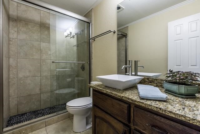 bathroom with ornamental molding, toilet, vanity, and a shower with shower door