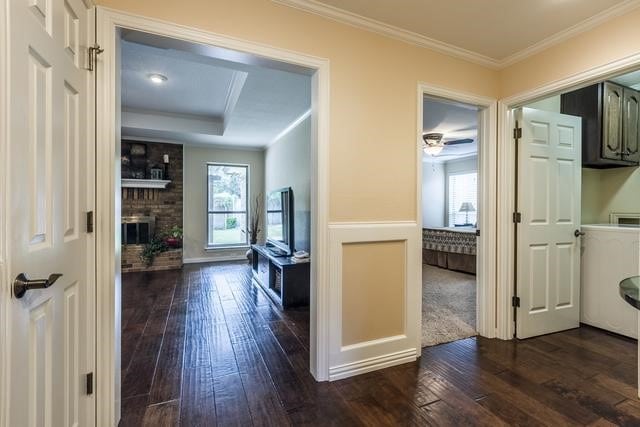 corridor featuring dark hardwood / wood-style floors, a tray ceiling, and ornamental molding