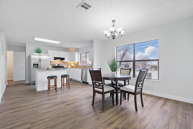 2160 Glenhaven Dr, Lewisville, TX 75067 - dining room with a textured ceiling, a chandelier, and wood finished floors