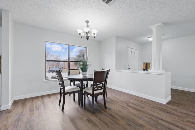 2160 Glenhaven Dr, Lewisville, TX 75067 - dining room with ornate columns, dark wood finished floors, a chandelier, and a textured ceiling