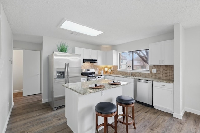 2160 Glenhaven Dr, Lewisville, TX 75067 - kitchen featuring stainless steel appliances, exhaust hood, wood finished floors, backsplash, and a textured ceiling