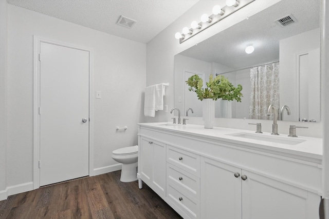 2160 Glenhaven Dr, Lewisville, TX 75067 - full bathroom featuring double vanity, a textured ceiling, wood finished floors, and a shower with shower curtain