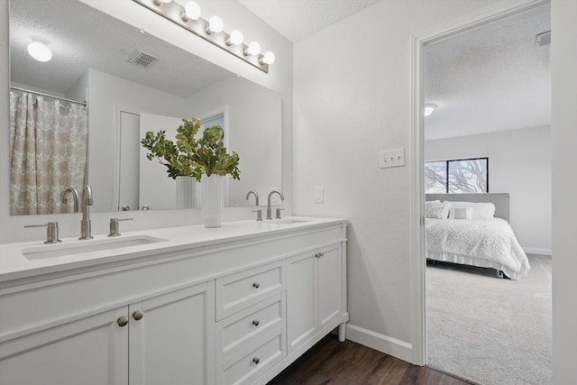 2160 Glenhaven Dr, Lewisville, TX 75067 - bathroom featuring a textured ceiling, double vanity, and wood finished floors