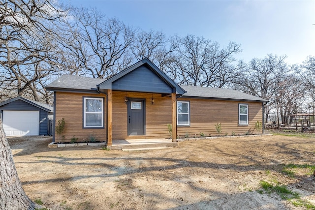 view of front of house featuring a porch, a garage, and an outbuilding