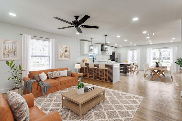 living room with light wood-style floors, ceiling fan, visible vents, and recessed lighting