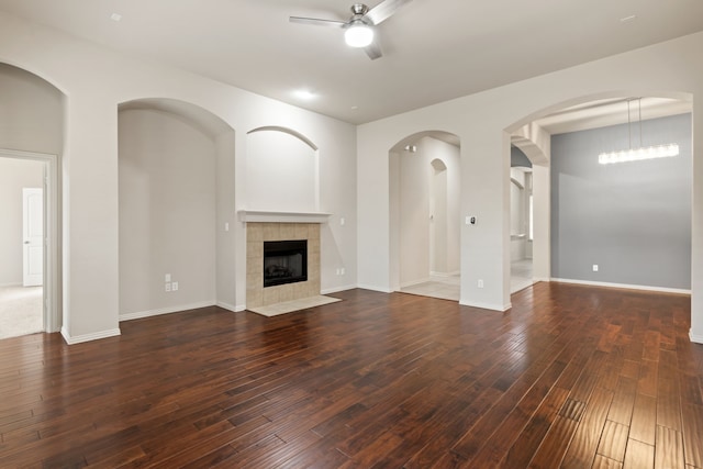 unfurnished living room with ceiling fan, dark wood-style flooring, a fireplace, and baseboards