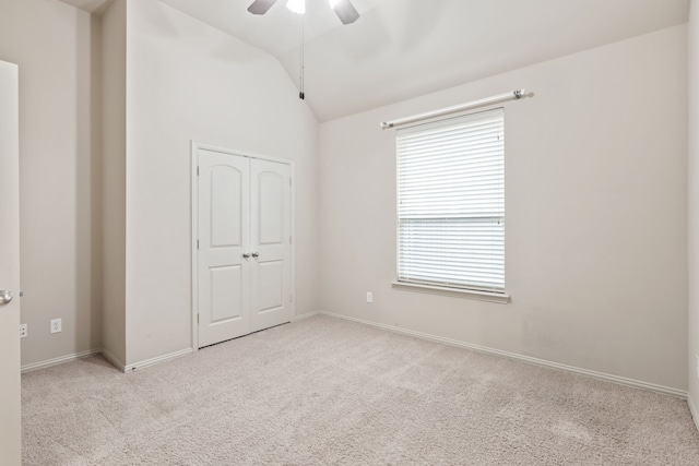 unfurnished bedroom featuring light carpet, a ceiling fan, vaulted ceiling, and a closet