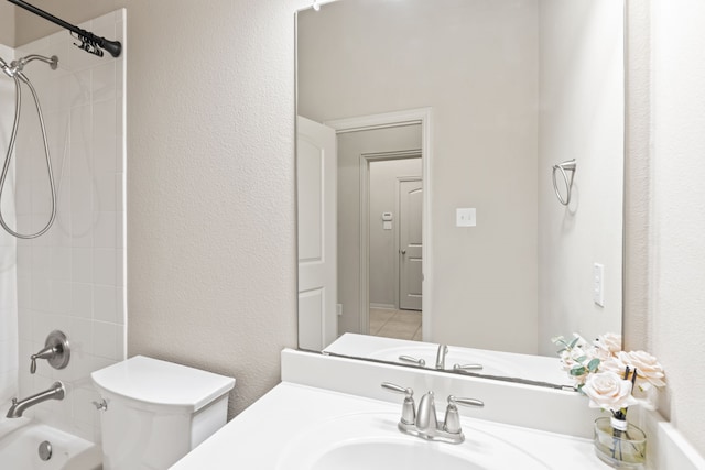 bathroom with toilet, a textured wall, vanity, and bathing tub / shower combination