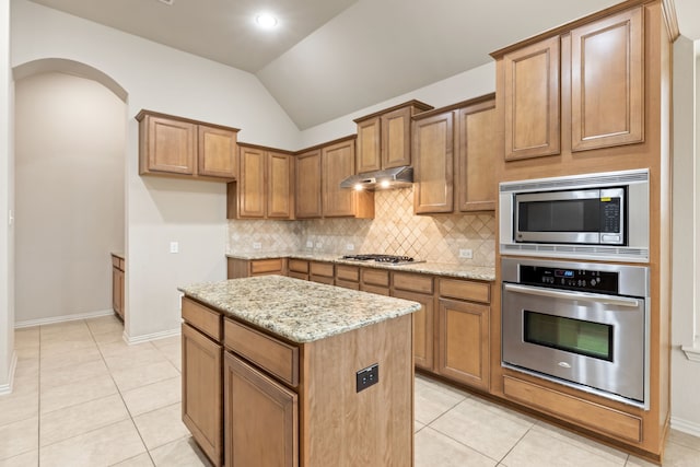 kitchen featuring under cabinet range hood, appliances with stainless steel finishes, brown cabinetry, and a center island