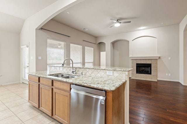 kitchen featuring a kitchen island with sink, a sink, open floor plan, light stone countertops, and dishwasher