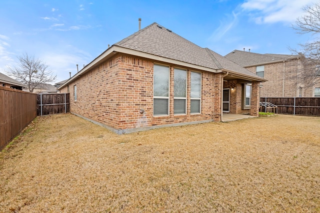 back of house with brick siding, a fenced backyard, and roof with shingles