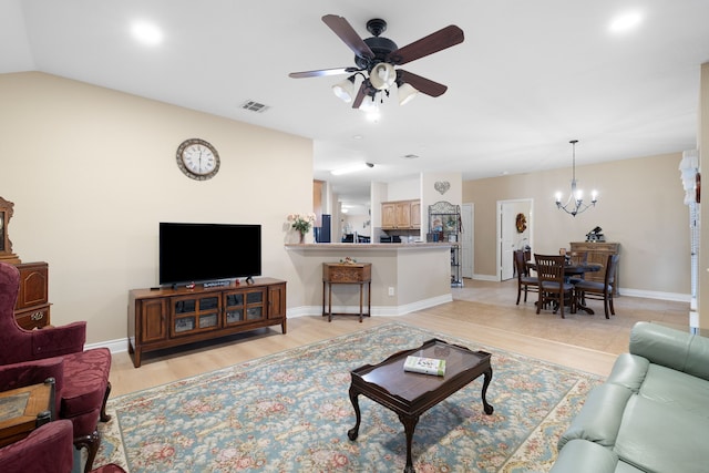 living room featuring ceiling fan with notable chandelier, light wood-type flooring, and vaulted ceiling