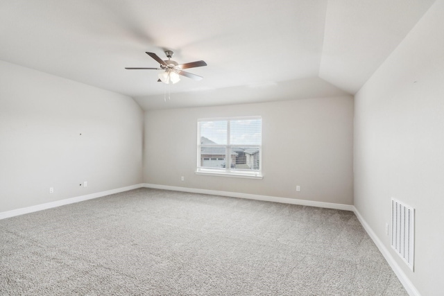 carpeted spare room with ceiling fan and vaulted ceiling