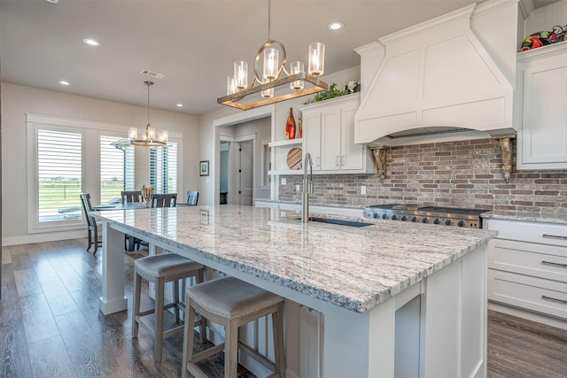 kitchen with white cabinetry, custom exhaust hood, pendant lighting, and a spacious island