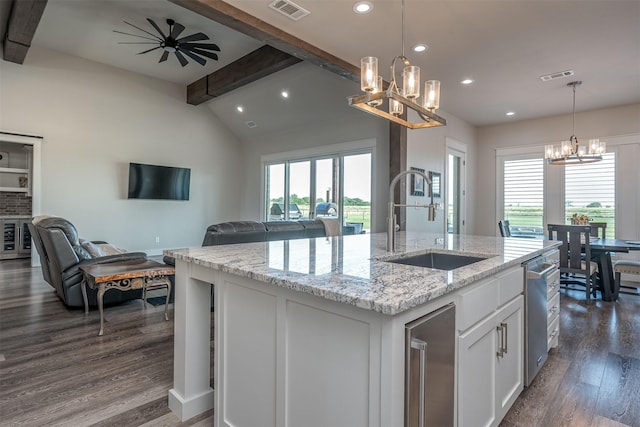 kitchen featuring a kitchen island with sink, open floor plan, visible vents, a sink, and white cabinetry