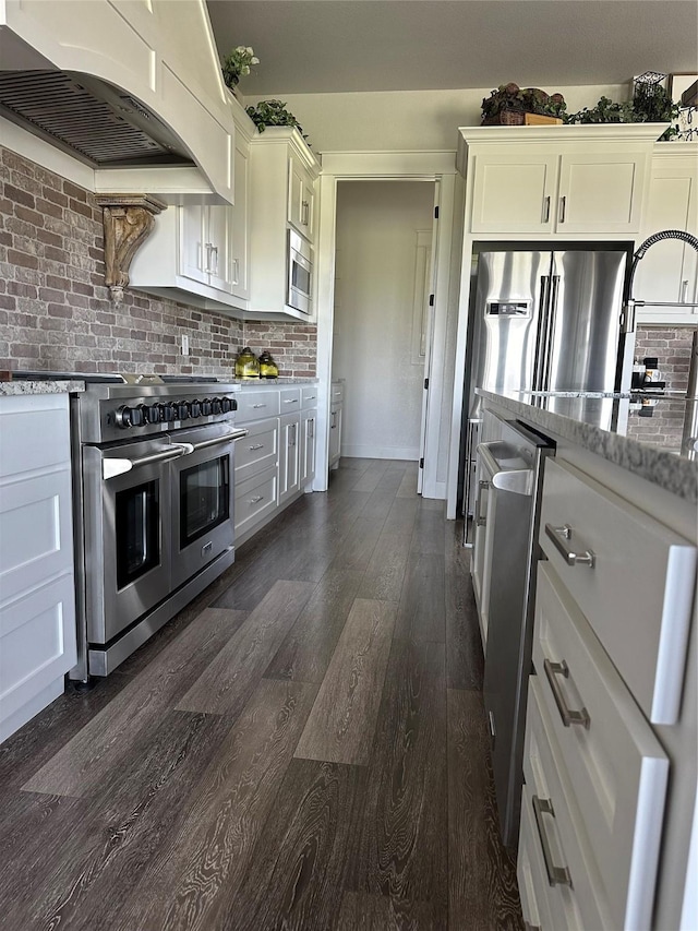 kitchen with stainless steel appliances, tasteful backsplash, dark wood-style floors, range hood, and light stone countertops