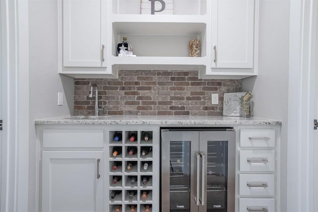 bar with decorative backsplash, indoor bar, beverage cooler, and a sink