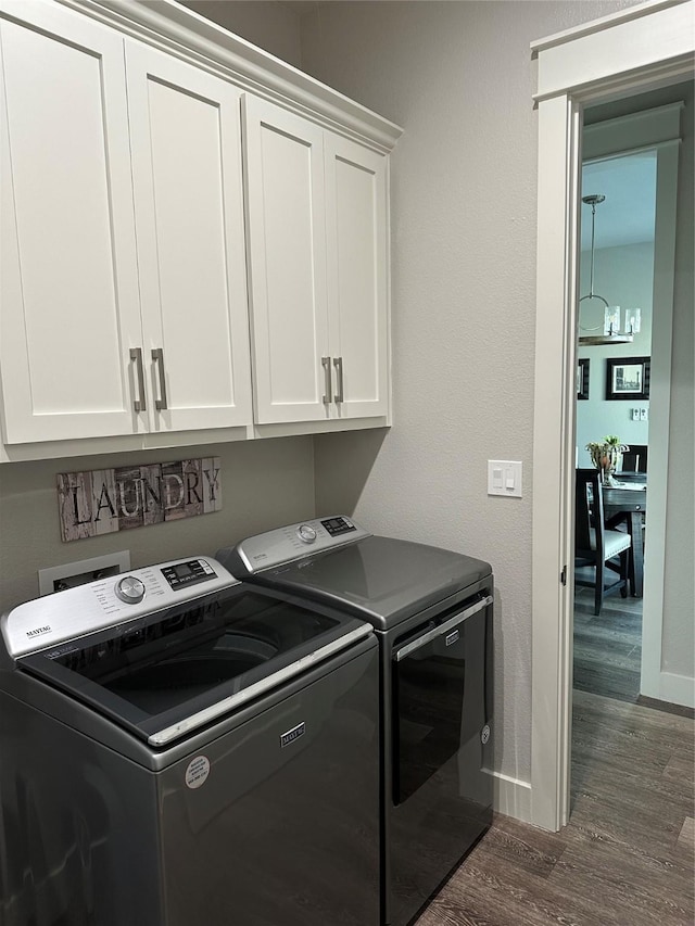 laundry room featuring washer and dryer, cabinet space, dark wood-style flooring, and baseboards