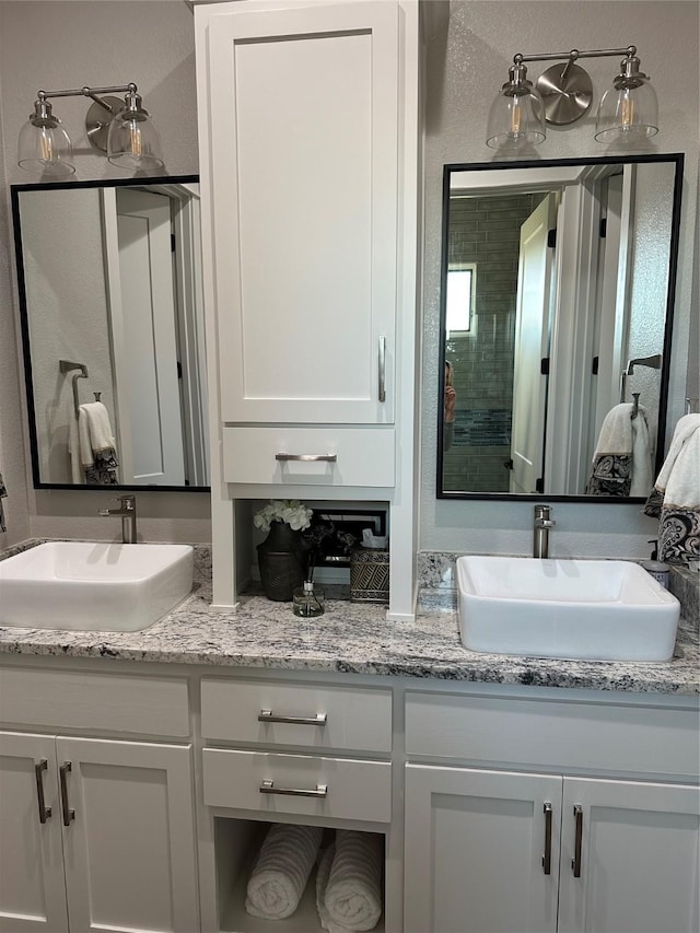 bathroom featuring double vanity, a textured wall, and a sink