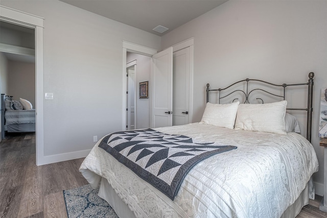 bedroom with wood finished floors, visible vents, and baseboards