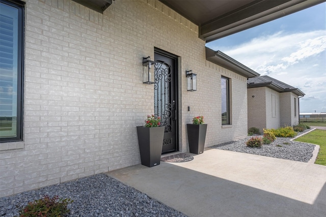 property entrance featuring a patio area and brick siding