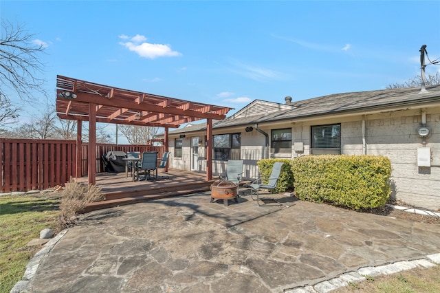 view of patio / terrace with fence, a fire pit, a wooden deck, and a pergola