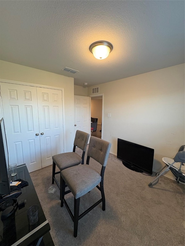 office space with visible vents, a textured ceiling, and dark colored carpet
