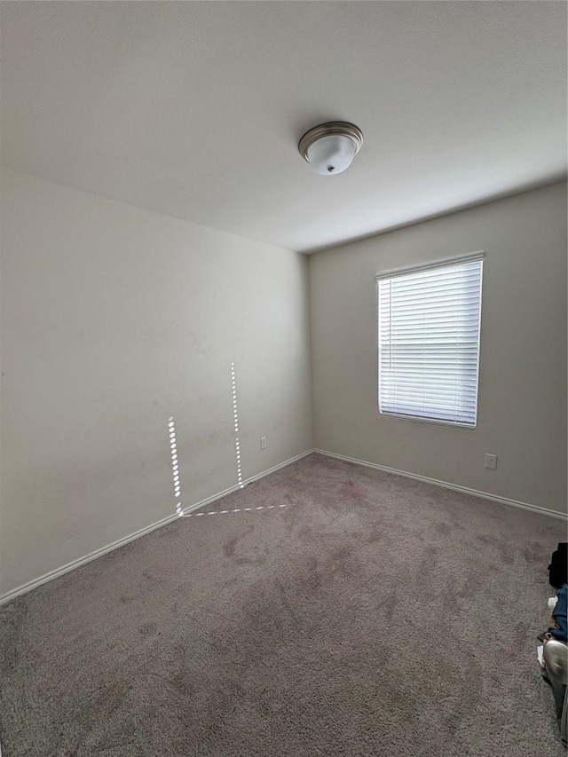 carpeted empty room featuring baseboards