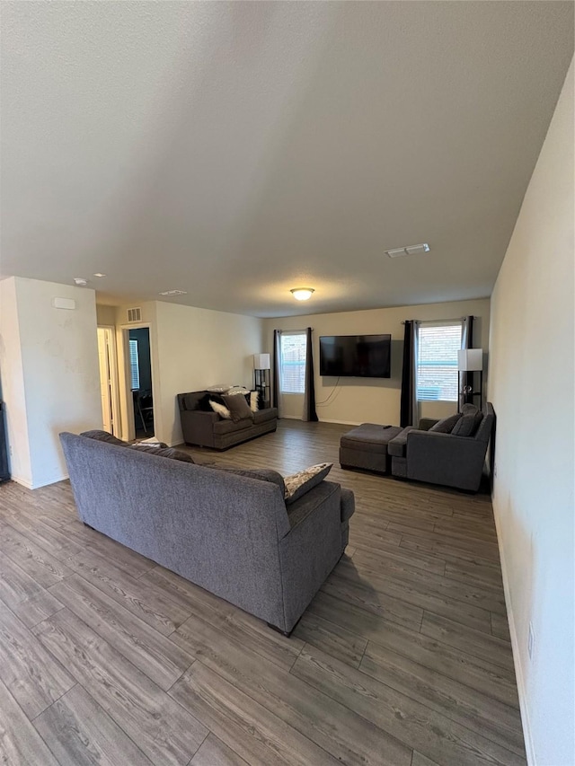 living room with visible vents, baseboards, and wood finished floors