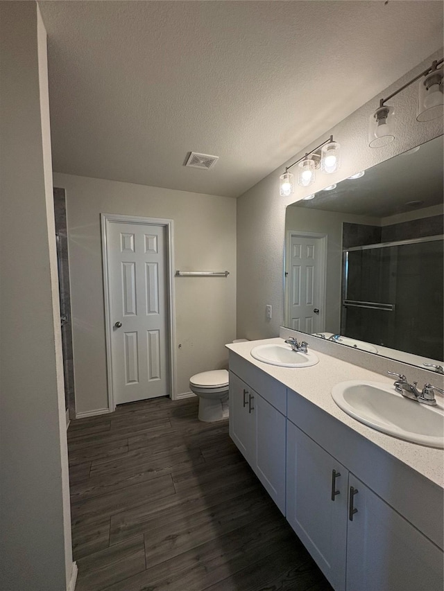 full bath featuring visible vents, a shower stall, wood finished floors, and a sink