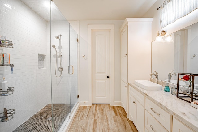 bathroom with wood-type flooring, a shower with shower door, and vanity