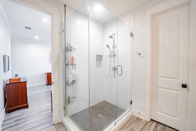 bathroom featuring hardwood / wood-style flooring, ornamental molding, and a shower with door