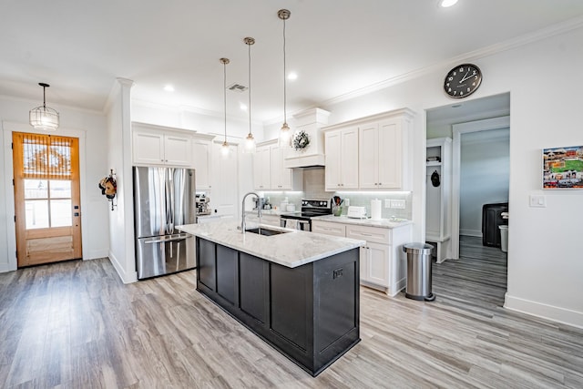 kitchen featuring appliances with stainless steel finishes, decorative light fixtures, sink, white cabinetry, and a kitchen island with sink