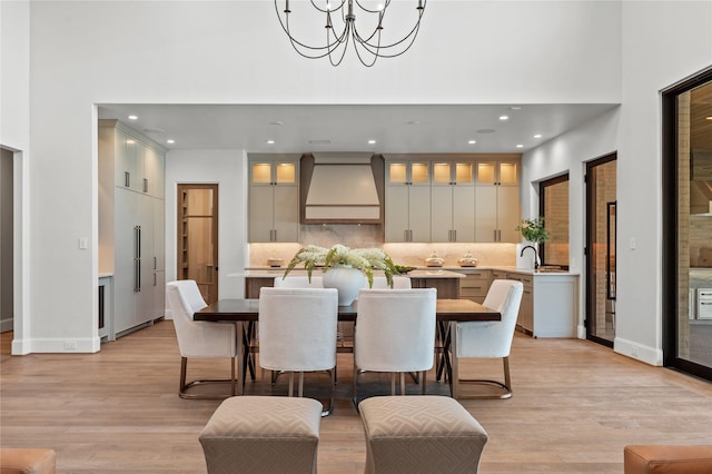 dining area with recessed lighting, light wood-style flooring, a high ceiling, a chandelier, and baseboards