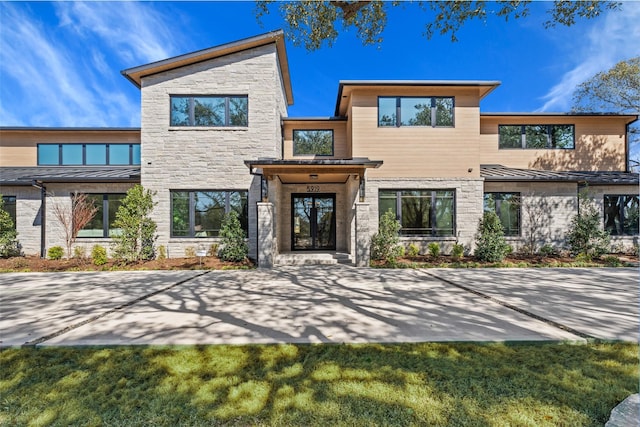 contemporary house featuring a standing seam roof, stone siding, and metal roof