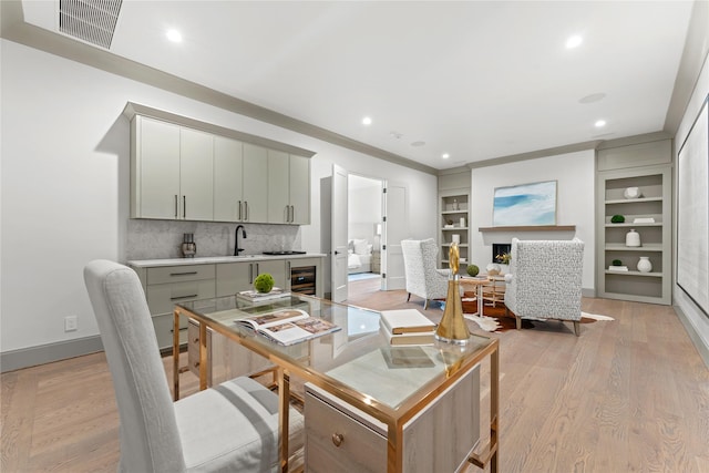 office with wine cooler, a fireplace, light wood finished floors, visible vents, and baseboards