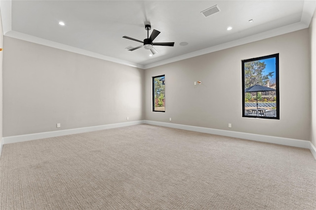 spare room featuring ceiling fan, baseboards, crown molding, and light colored carpet