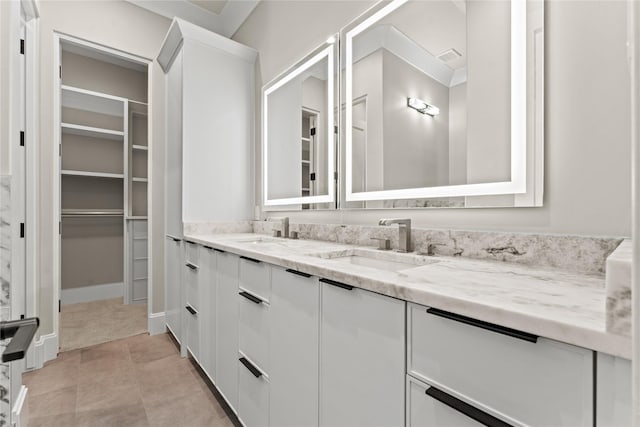 bathroom featuring double vanity, tile patterned flooring, a sink, and a walk in closet