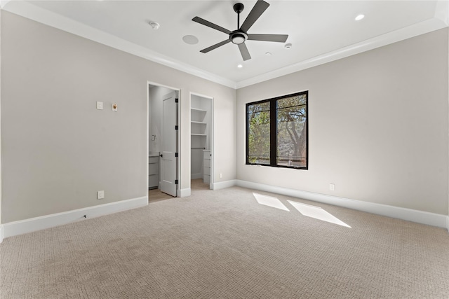 unfurnished bedroom with recessed lighting, light colored carpet, baseboards, ornamental molding, and a walk in closet